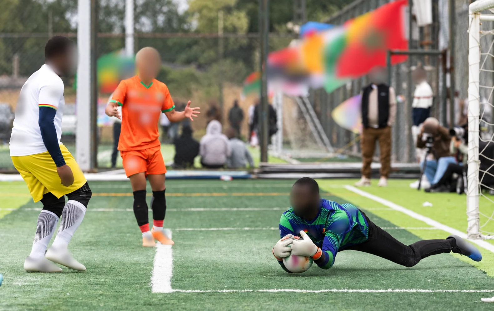 Privacy-edited football project image showing a blue-and-green goalkeeper top and contrasting outfield kits.